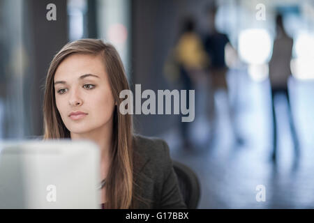 Young businesswoman sitting at desk, using computer