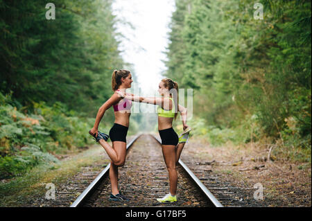 Young woman and teenage girl exercising on rural train track Stock Photo