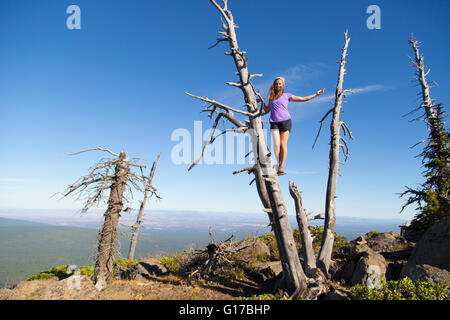 Young woman standing on dead tree, Black Buttes, Oregon, USA Stock Photo