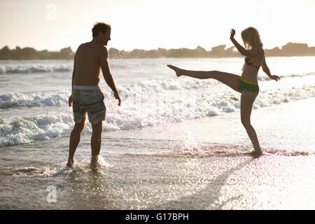 Couple on beach frolicking in ocean Stock Photo
