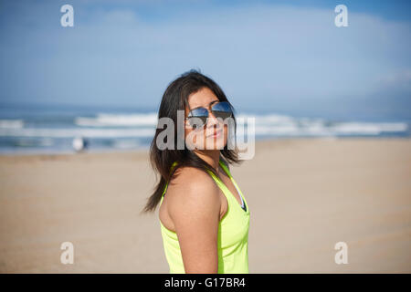 Woman wearing sunglasses on beach looking at camera Stock Photo