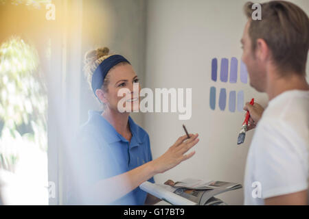 Couple holding brochure discussing paint colours on wall Stock Photo