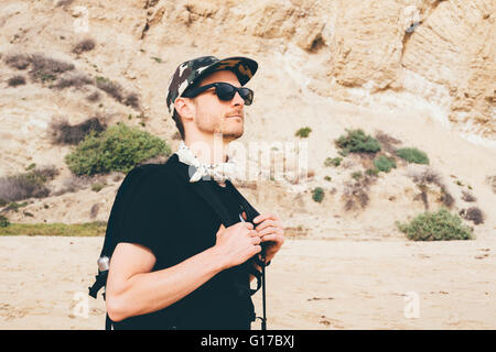 Male hiker wearing baseball cap walking on beach, Crystal Cove State Park, Laguna Beach, California, USA Stock Photo