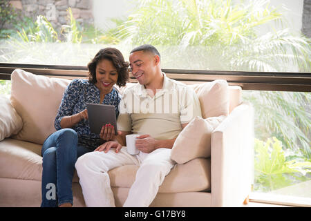 Couple using digital tablet on sofa Stock Photo