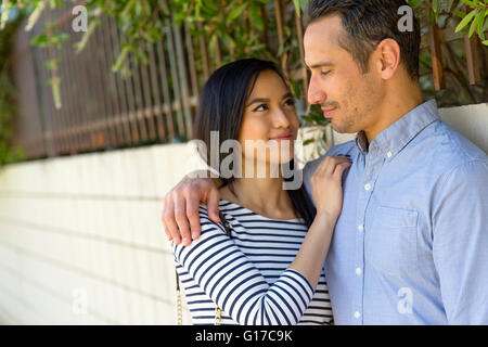 Couple in street leaning against wall smiling Stock Photo