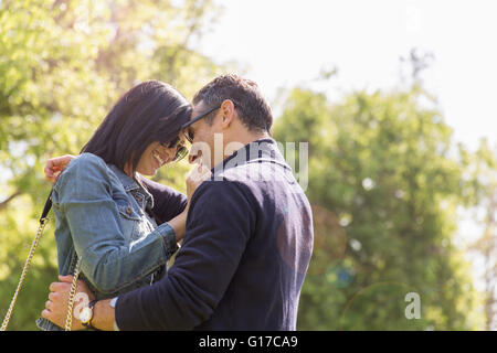 Couple in park face to face hugging and smiling Stock Photo