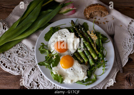 Roasted asparagus with Parmesan cheese on a bed of rucola salad and topped with fried eggs
