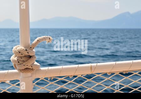 Marine knot detail on steel boat banister with blurred sea in background Stock Photo