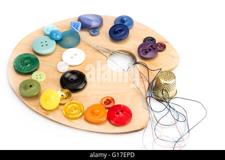 buttons, thimble, needle and thread laid on a palette on a white background Stock Photo