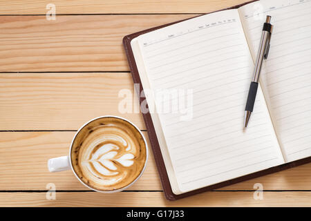 blank notebook with pen and cup of coffee on wooden table, office desk  concept Stock Photo