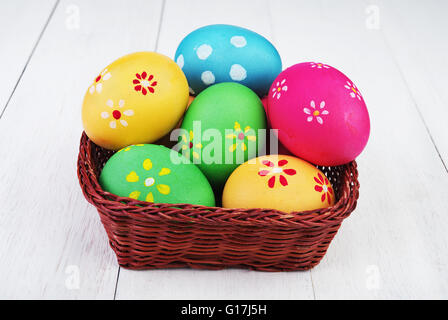 multi colored easter eggs in basket on vintage wooden background Stock Photo