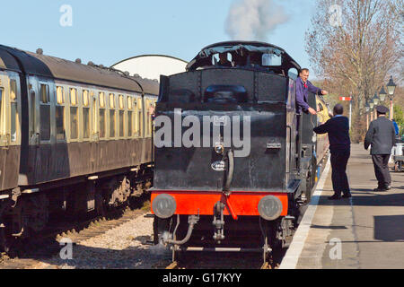 Fireman and signalman exchange the single line token at Williton station on the West Somerset Railway, England, UK Stock Photo