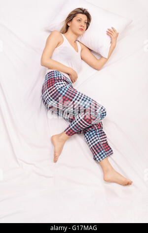 Vertical top view shot of a blond woman in pajamas suffering from insomnia Stock Photo