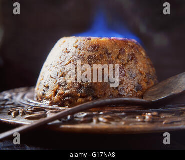 Flaming brandy Christmas pudding on wooden board Stock Photo