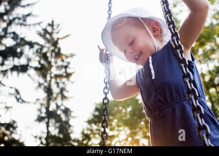 Baby girl playing on park swing, low angle view Stock Photo
