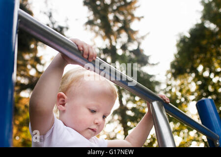 Baby girl on climbing frame at park Stock Photo