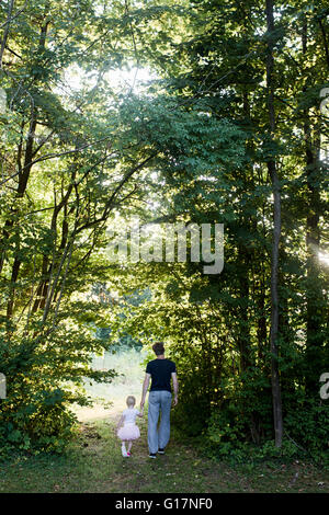 Rear view of father and daughter walking hand in hand in a park Stock ...