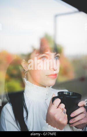 Young woman with mug looking out of window Stock Photo