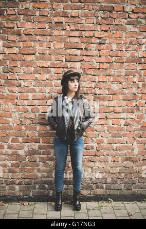 Young woman in front of brick wall Stock Photo