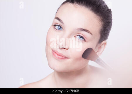 Portrait of beautiful young woman applying blusher Stock Photo