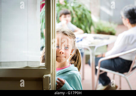 Girl peering around cafe doorway, Florence, Italy Stock Photo