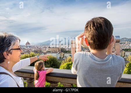 Senior woman and grandson looking at cityscape from coin operated binoculars, Florence, Italy Stock Photo