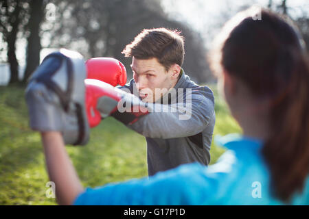Young man and woman doing boxing training in park Stock Photo