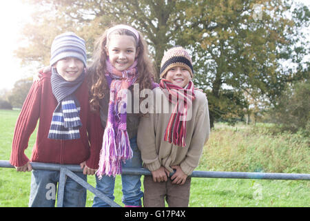 Portrait of three children leaning on fence, smiling Stock Photo