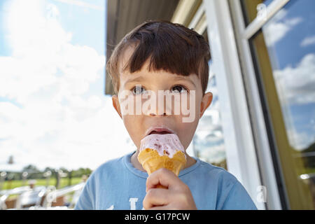 Boy enjoying ice-cream cone in front of shop Stock Photo
