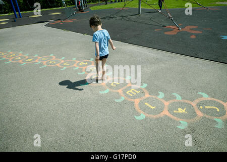 Boy playing hopscotch in playground, Richmond, London Stock Photo