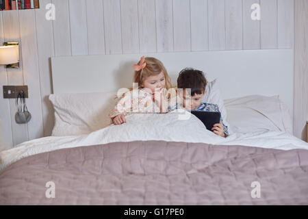 Children using digital tablet in bed Stock Photo