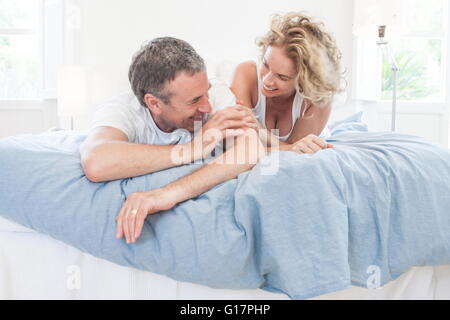 Mature couple lying on bed laughing Stock Photo