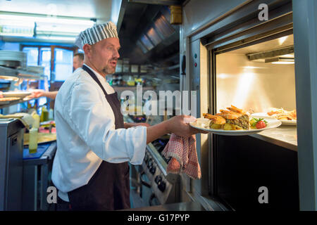 Chef placing dish in lift in traditional Italian restaurant kitchen