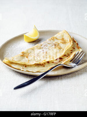 Pancake with lemon wedge and sugar on plate Stock Photo