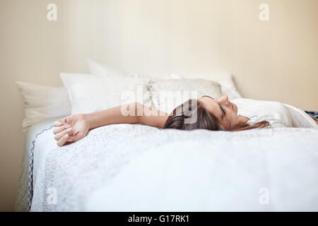 Surface level view of young woman lying back on bed Stock Photo