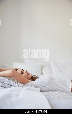 Surface view of beautiful young woman lying back on bed Stock Photo