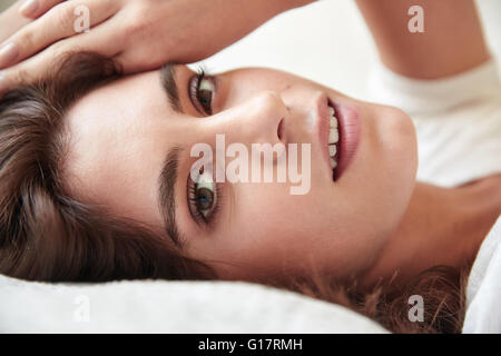 Close up of beautiful young woman lying on bed