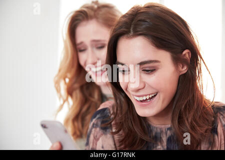 Two young women laughing at smartphone texts Stock Photo