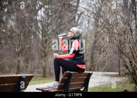 Mature woman training in park, drinking bottled water Stock Photo