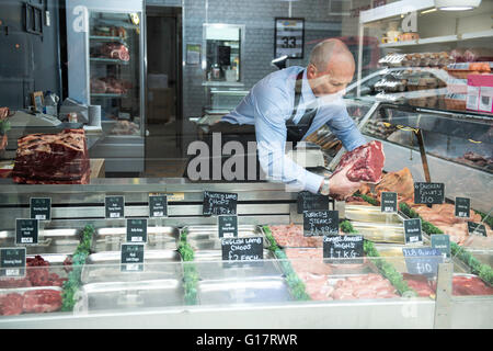 Butcher preparing window display in butcher's shop Stock Photo