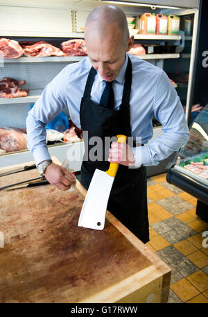 Butcher cleaning meat cleaver in butcher's shop Stock Photo