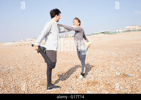 Man and woman training, standing on one leg on Brighton beach Stock Photo