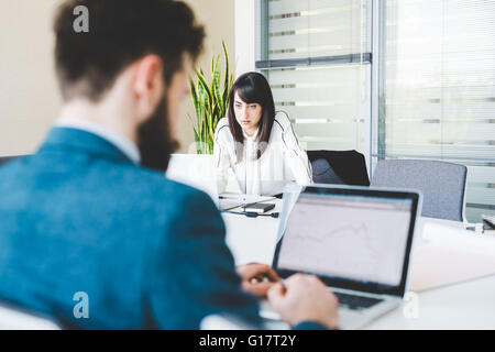 Businesswoman and man using laptops in office Stock Photo
