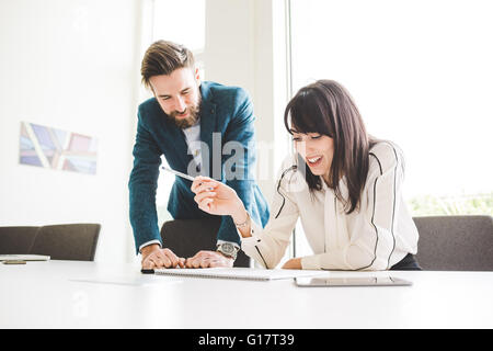 Young businessman and woman writing on notepad at conference table Stock Photo