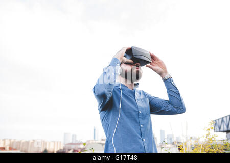 Young male designer testing virtual reality headset on office roof terrace Stock Photo