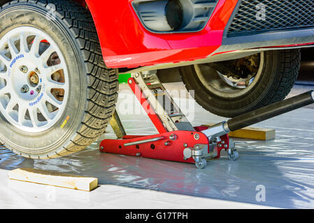 Emmaboda, Sweden - May 7, 2016: 41st South Swedish Rally in service depot. Red car lifted by hydraulic floor jack. Stock Photo
