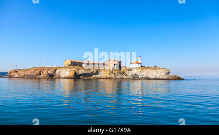 St Anastasia Island in Burgas bay, Black Sea, Bulgaria. Lighthouse tower and old wooden buildings on rocky coast Stock Photo