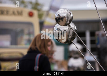 Harrogate Spring Flower Show 2016 (North Yorkshire, England) - close-up of garden ornaments (mirror spheres) with reflections of people passing. Stock Photo