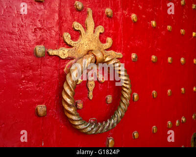 Red painted historic brass studded Gothic church entrance door detail  to Winchester Cathedral Hampshire UK Stock Photo