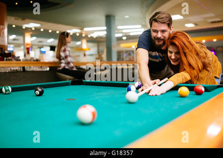 Beautiful happy couple playing billiards Stock Photo